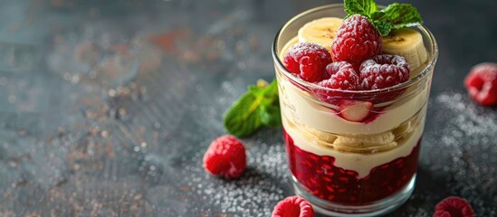 Yogurt dessert layers with applesauce, banana, and raspberries, garnished with mint, served in a glass with copy space image.