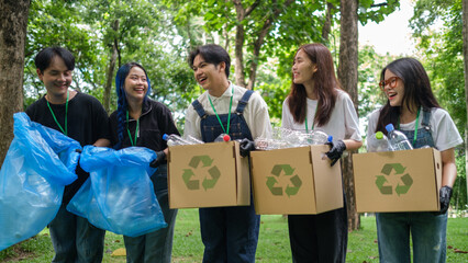 Group of young volunteers with recycling box and garbage bag standing in park. Community, environmental protection and recycling concept.