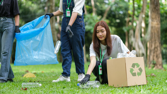 A group of young volunteers is actively participating in an outdoor clean-up activity in a park.