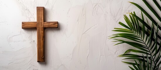 A wooden cross and palm fronds typically employed by Catholic Christians for Palm Sunday set against a white backdrop with available copy space image
