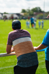 Viewer of a Football Game Standing on the Sideline Watching the Soccer Players Play on the Green Field