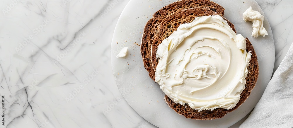Aufkleber Top down view of a slice of bread spread with delicious cream cheese on a white marble surface with room for text in the image s background. Creative banner. Copyspace image
