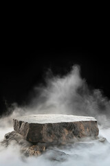 Empty stone product display podium surrounded by mist against black backdrop 
