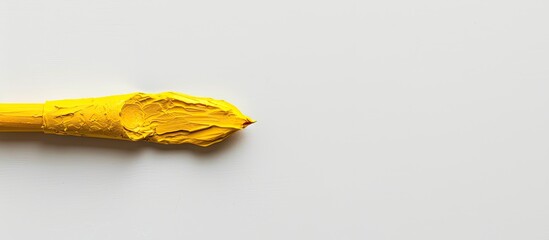 A yellow Plasticine brush stands alone on a white backdrop providing ample copy space image