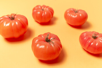 Close-up of pink tomatoes on background of pastel yellow color. Top view. Colourful pattern.