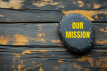 Our mission message written on black stone with wooden background background. Conceptual our mission symbol. Copy space.