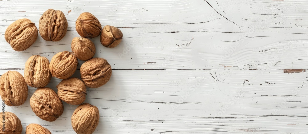 Poster A variety of walnuts alongside a nutcracker arranged on a white wooden surface providing room for text in the image. Copy space image. Place for adding text and design