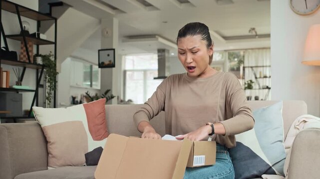 Medium long shot of disappointed Asian woman getting wrong pair of leather shoes in parcel at home