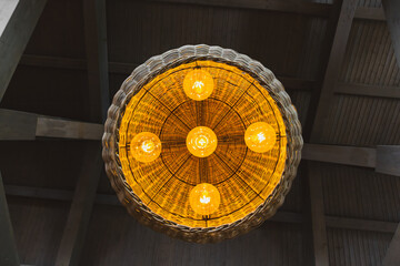 Large ceiling lamp hanging from wooden ceiling, viewed from below