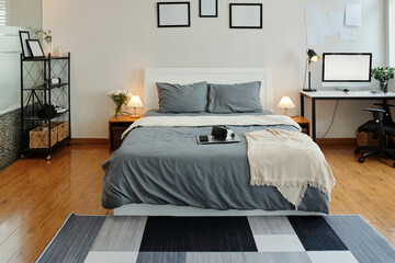 Modern bedroom with comfortable bed and workplace with computer