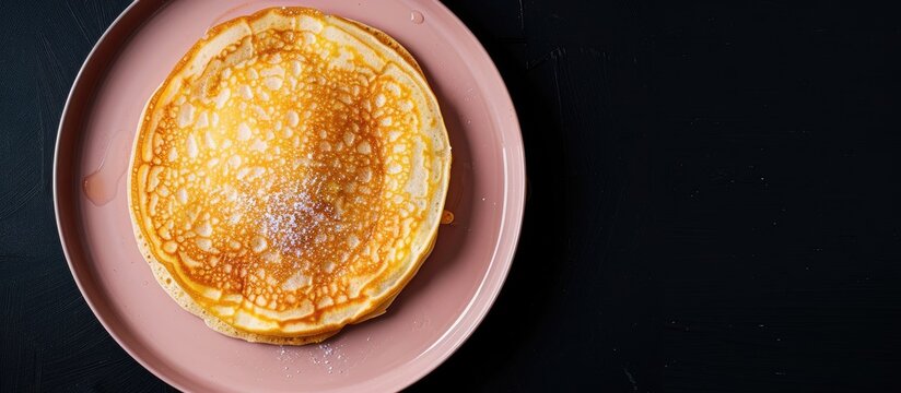 Top view of a homemade apple Dutch pannekoek pancake served on a pink plate against a black backdrop captured as a flat lay image with copy space available