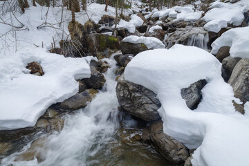 Flowing creek under the heavy snow