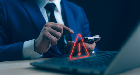 A Businessman developer working and using laptop computer with triangle caution warning sign for...