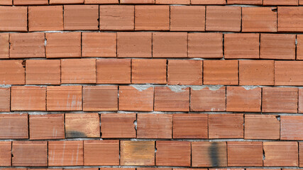 Red brick wall texture of an unfinished house under construction, showing a rough, tiled surface.