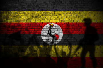 uganda flag painting on brick wall and Protesters shadow
