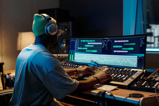 Music producer working on mixing tracks in professional recording studio equipped with modern technology and audio equipment at nighttime