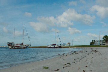 Beach sailboats after a storm at Gulfport Beach Florida. Boats and yachts washed in from Boca Ciega Bay after strong winds. Early Morning Sun with room for copy. Blue Skies and small waves water