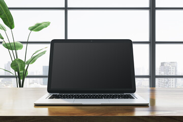 Fototapeta premium Modern laptop on wooden desk in front of large window with city view. 3D Rendering