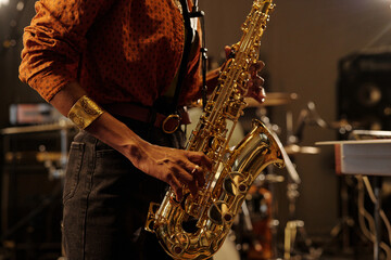 Close-up of person playing saxophone, capturing the energy and focus during performance in...