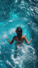 A woman is swimming in a pool with a lot of water splashing around her. The water is blue and the woman is wearing a bikini