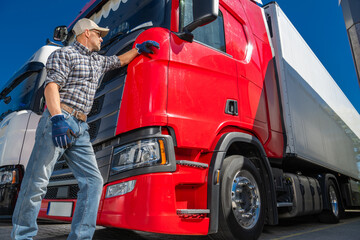 Truck Driver Inspecting a Red Truck in a Sunny Outdoor Freight Yard
