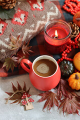 Autumn still life with red mug and warm brown knitted sweater. Cloe up photo of colorful autumn composition. 