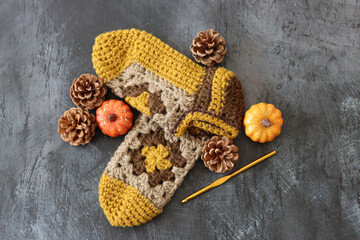 Crocheted sleepers on dark grey background with space for text. Handmade knitted baby booties made of wool. Autumn hobby concept. 