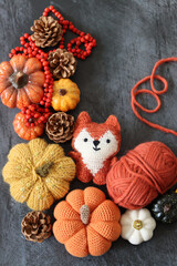 Halloween decoration with pumpkins, crocheted Fox toy and orange wool yarn on grey background with space for text. Handmade autumn gift. 