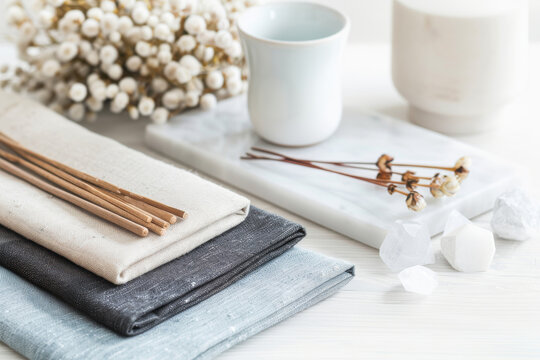 A serene tabletop arrangement featuring linens, a cup, and decorative elements for a calming aesthetic.