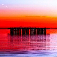 Fototapeta premium Pier Silhouette with Stunning Reflection at Sunset