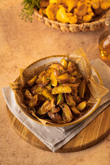 Vegetarian dish fried potatoes with garlic, parsley and chanterelle mushrooms closeup on a plate on the table. Vertical
