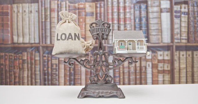 Home loan, reverse mortgage and saving for a real estate concept : House model, loan bag on a balance scale, depicts saving for a house or flat manageable and make a dream of owning a home come true.