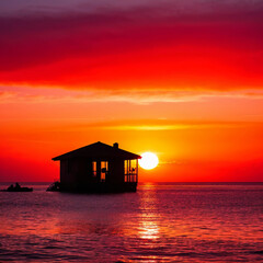 Tranquil Sunset with a Silhouette of a House on the Water