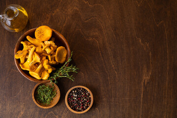 Fresh chanterelles in a wooden bowl on a dark wooden background. Wild mushrooms, ingredients for cooking.