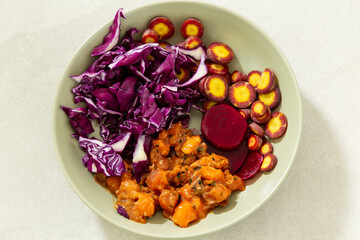 Flat lay view of healthy meal including salmon tartare, cosmic purple carrots in thin slices showing their bright yellow interior, red cabbage and beets in pale green bowl
