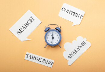 A blue alarm clock sits on a table with a bunch of paper cutouts around it