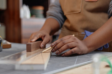 Close-up of hands holding pencil and ruler on wooden surface, illustrating precise woodworking measurement in a workshop environment