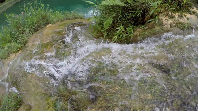 A man slides down a natural water slide into a river in Semuc Champey, Guatemala