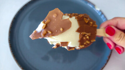 A cracked and bitten ice cream with almonds and chocolate coating on a plate  