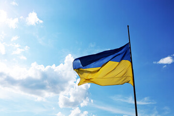 The Ukrainian flag flies with a blue sky and light clouds in the background