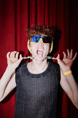 Young excited man in stylish attire and sunglasses holding neck accessory and keeping his mouth...