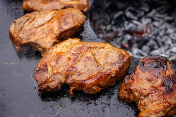 Grilled steaks on a round grill over coals, top view