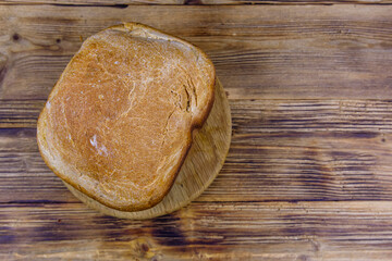 Loaf of freshly baked bread on a wooden table. Top view