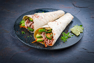 Italian style wrap piada wheat tortilla with tuna fish, vegetable and avocado served as closeup on...