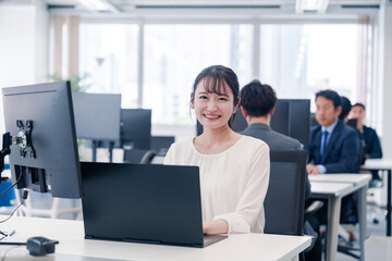 オフィスで笑顔でデスクワークをする若い女性