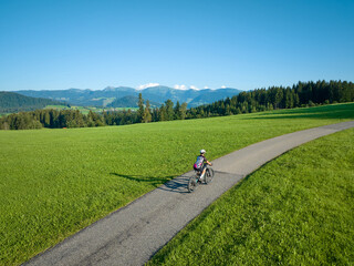pretty senior woman riding her electric mountain bike  in the Allgaeu mountains near Oberstaufen and Stiefenhofen, Bavaria, Germany
