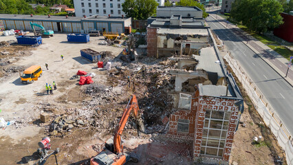 Drone photography of machinery dismantling a house and removing ruble during sunny summer day.