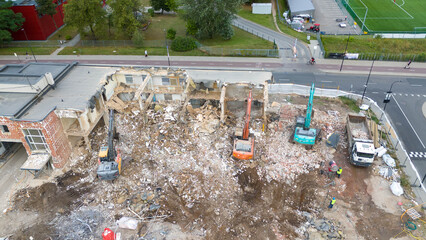Drone photography of machinery dismantling a house and removing ruble during sunny summer day.