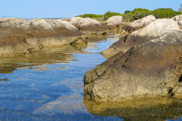 Rocky beach in the Mediterranean sea with clear water and stones.
