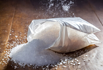 Salt in open transparent plastic pouch bag on wooden table